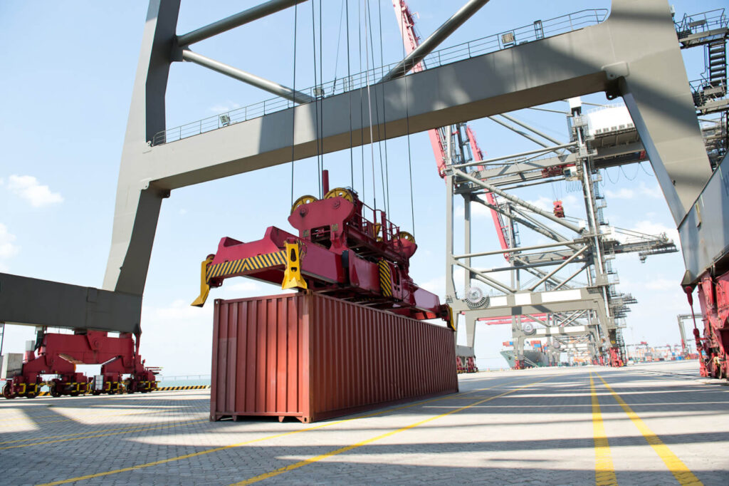 Foto von einem Container im Hafen unter einer Containerbrücke